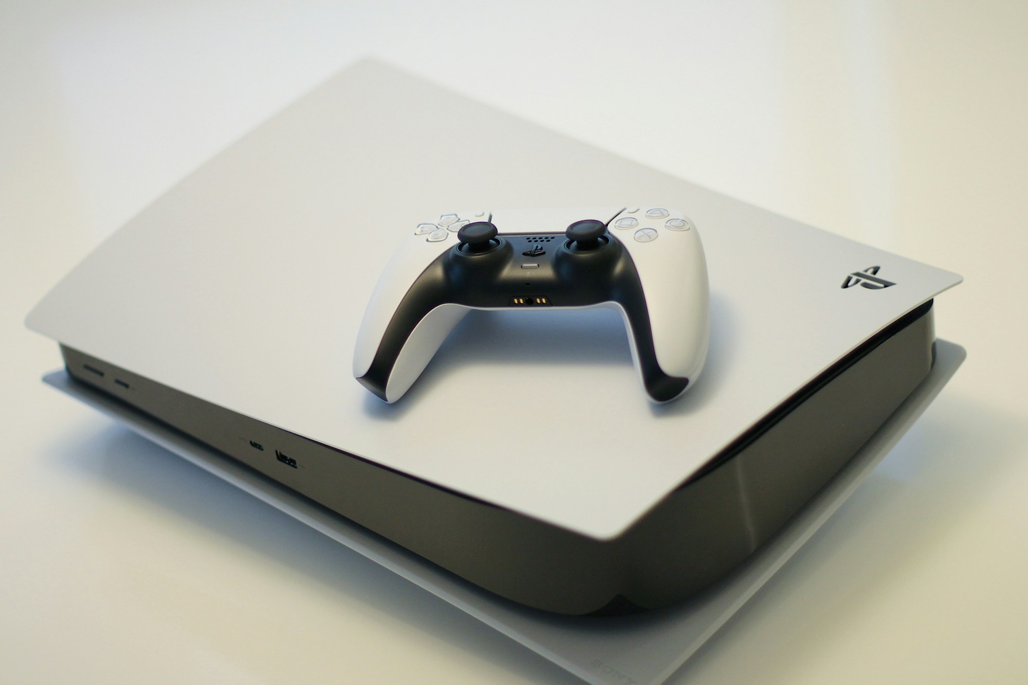 White PlayStation 5 console lying flat with a DualSense controller resting on top